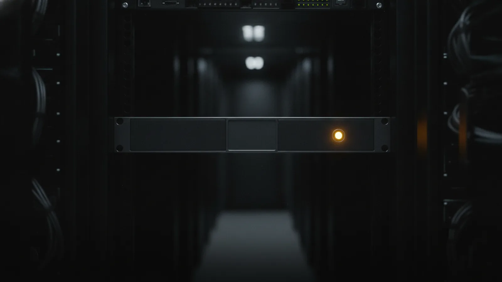 A racked firewall in a dark data center, its LED panel dark except for a single amber alarm LED glowing.