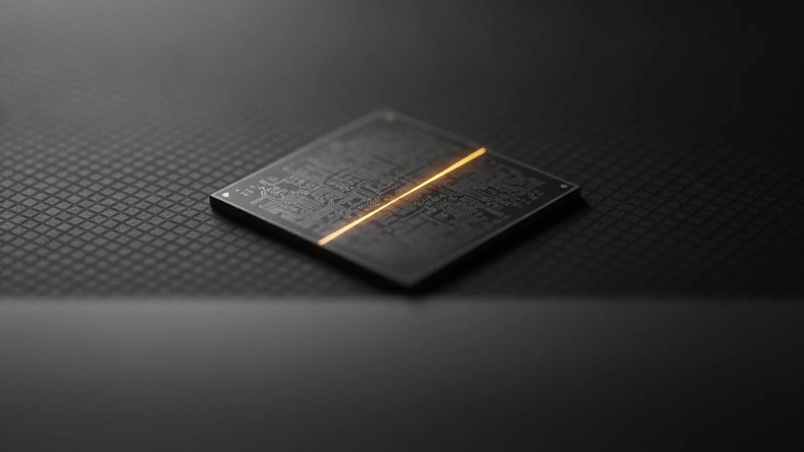 Un unique processeur nu posé sur un tapis antistatique sombre, une seule piste de cuivre éclairée en ambre le long de sa surface, le reste du circuit en gris anthracite.